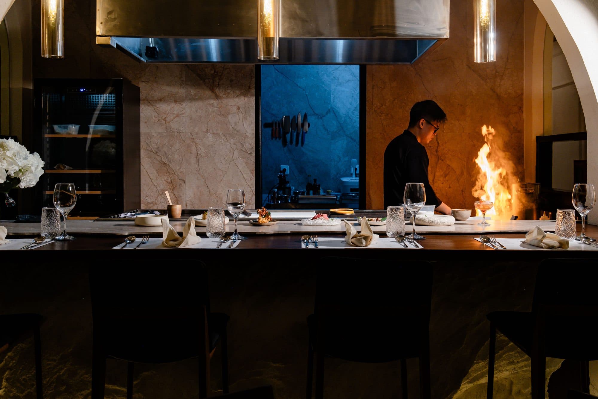 Chef cooking over an open flame at the Kumo counter inside Riviera Boutique Hotel Ubud.