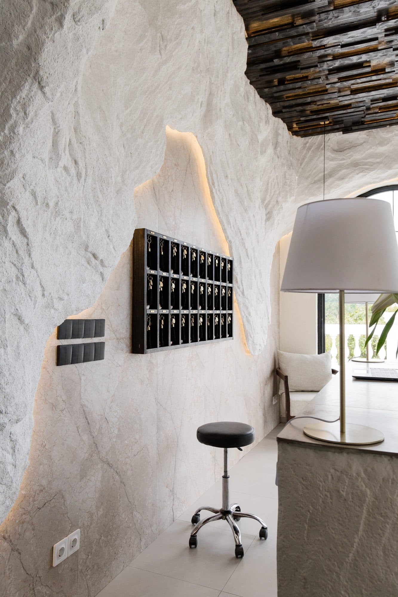 A calm treatment room with a textured stone wall and soft lighting at Riviera Spa in Ubud